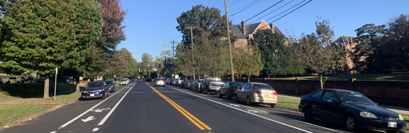 A view from the middle of Rivermont Avenue facing north, featuring car lanes, bike lanes, parking lanes, trees, sidewalks, buildings, etc.